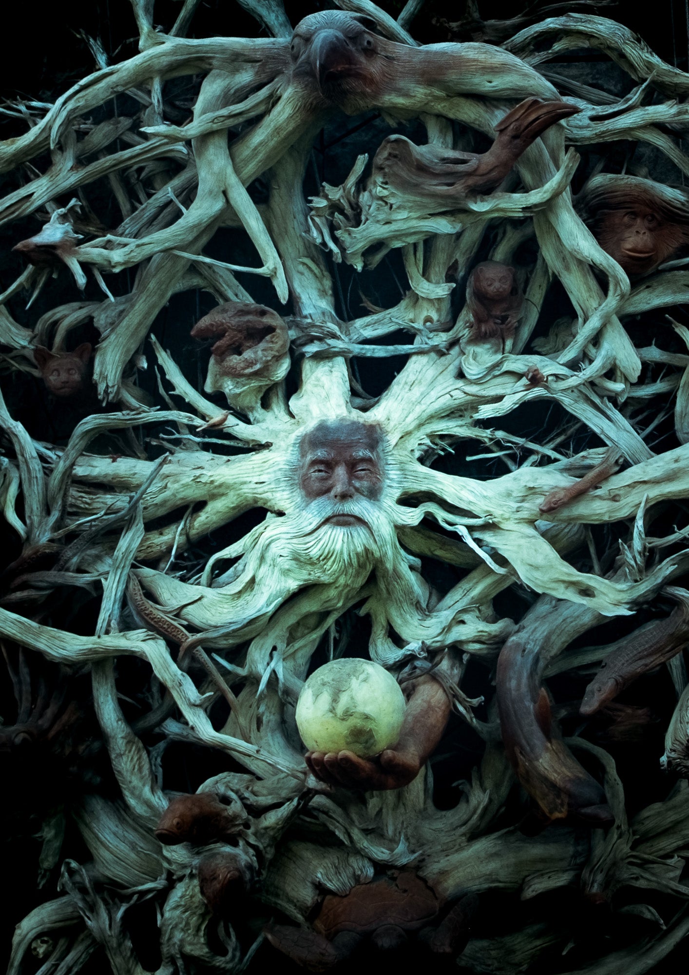 Artistic depiction of a face made from dried plants with a small fruit at the center.